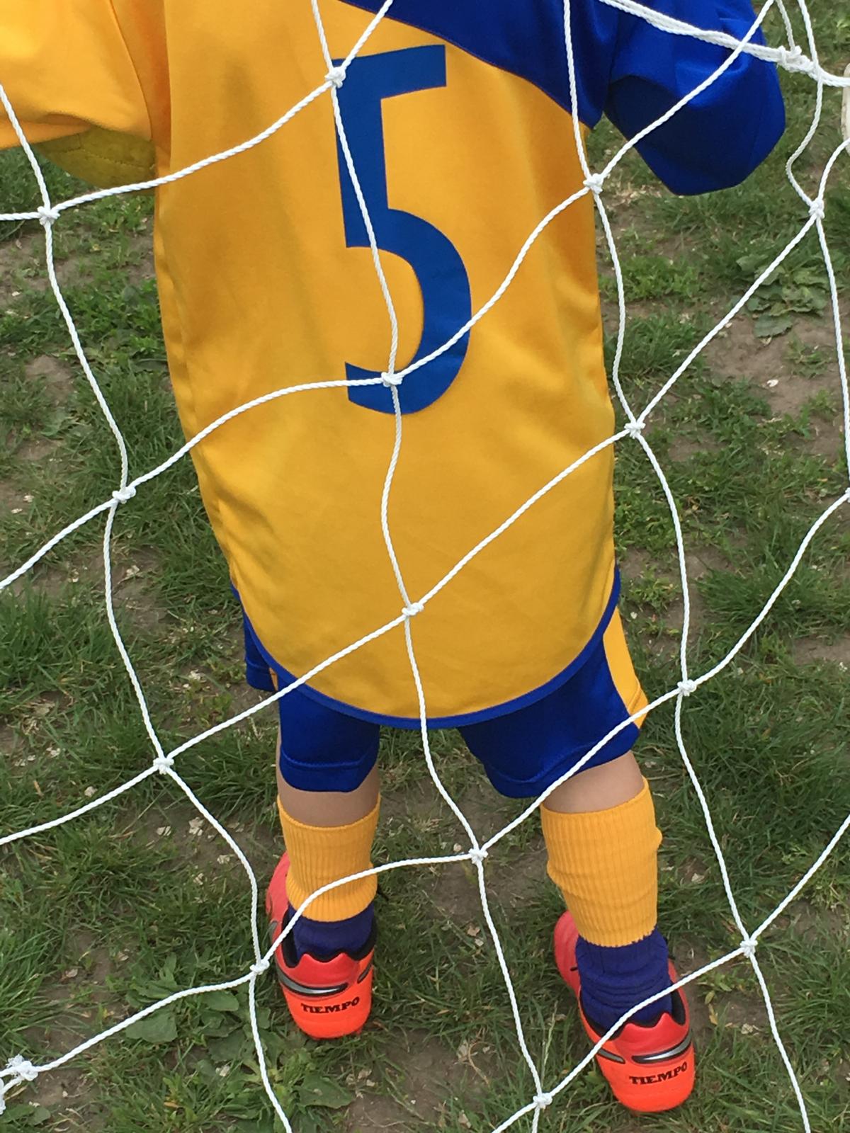 Home 9 young-player-in-number-five-kit-behind-goal-net